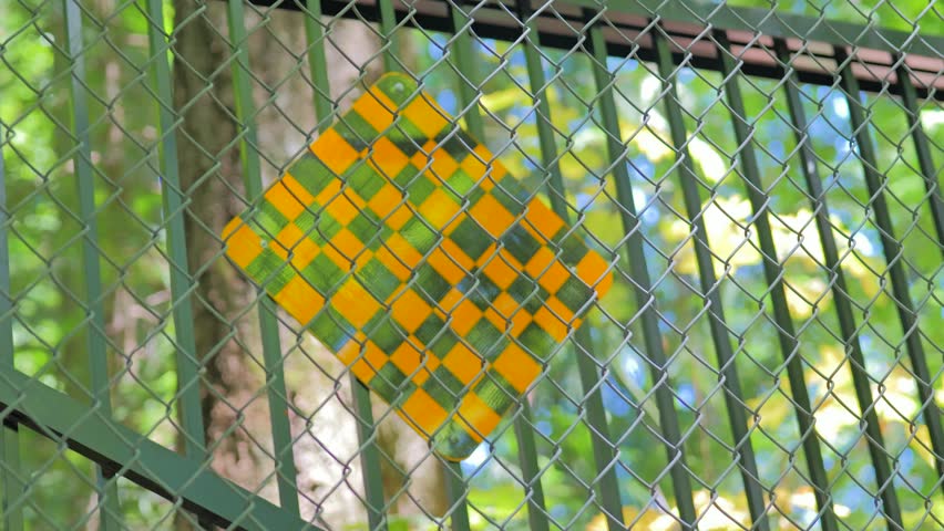 Close up of chain link security fence with out of focus trees
