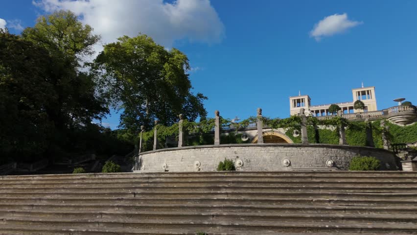 Stone terrace steps lead up toward a sculpted garden wall and palace building in Sanssouci Park, Potsdam.