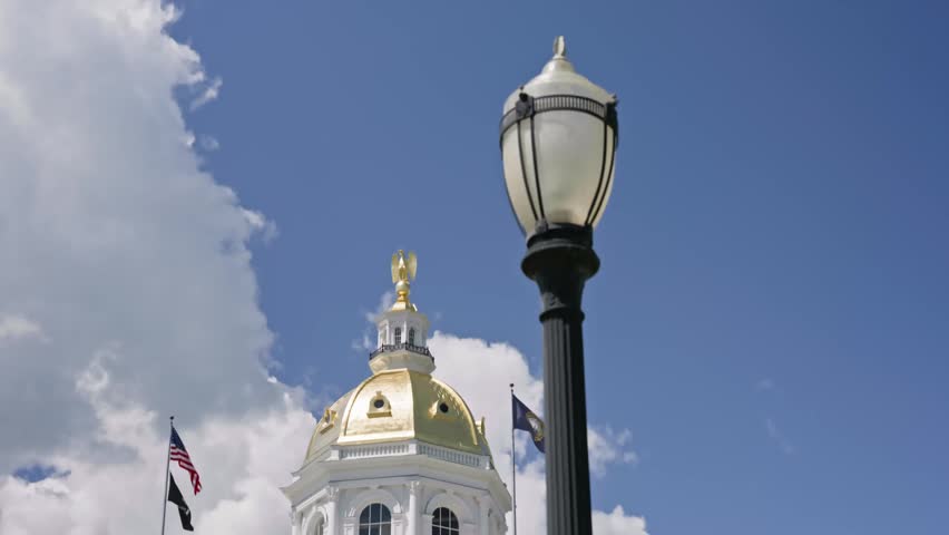 Cinematic tilt down and push in featuring a decorative light post with the New Hampshire State House in the background in Concord New Hampshire on a bright summer day.