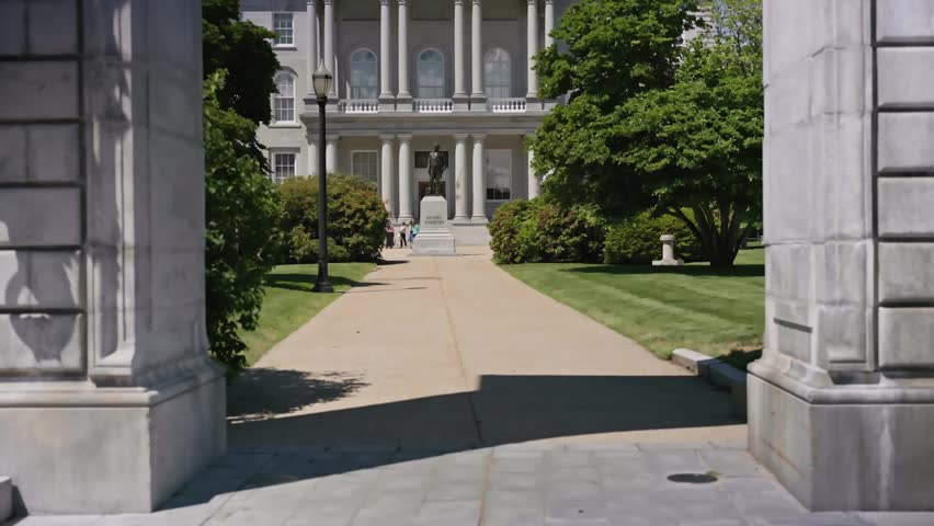 Cinematic dolly back and upward movement revealing the Soldiers and Sailors Memorial Arch on the grounds of the New Hampshire State House in Concord New Hampshire during a bright summer day.