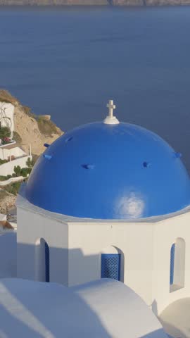 Vertical blue domed church with caldera views in the background in Oía, Santorini, Greece.