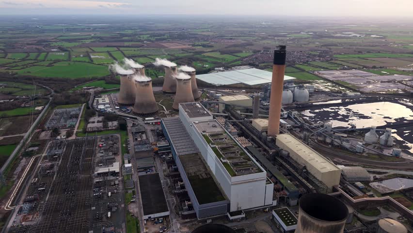 Aerial view of Drax power station with cooling towers emitting water vapour at sunset, UK.