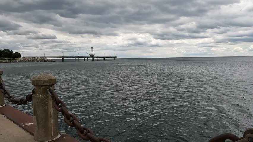 Wide view of a lakeside park and pier along Lake Ontario on a cool cloudy day, capturing a peaceful Canadian waterfront in 60fps.
