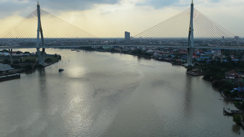 Centered aerial of Bhumibol Bridge crossing Chao Phraya River under soft evening light, drone medium ascend approach