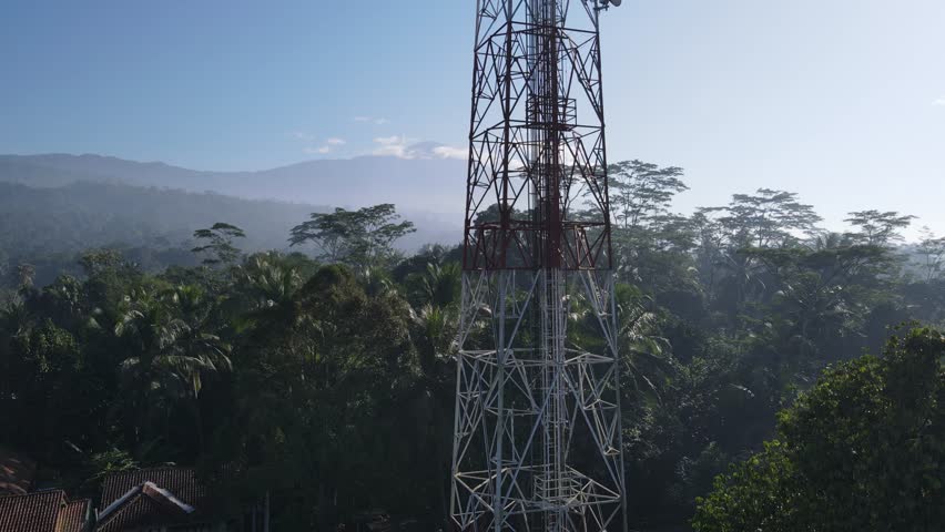Aerial scenery of Telecommunications tower in rural landscape surrounded by villages and its trees and mountains seen from afar