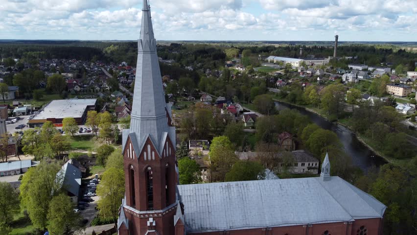 A drone view of Church of Apostle Evangelist St Matthew with urban surroundings under cloudy sky in Anyksciai, Lithuania