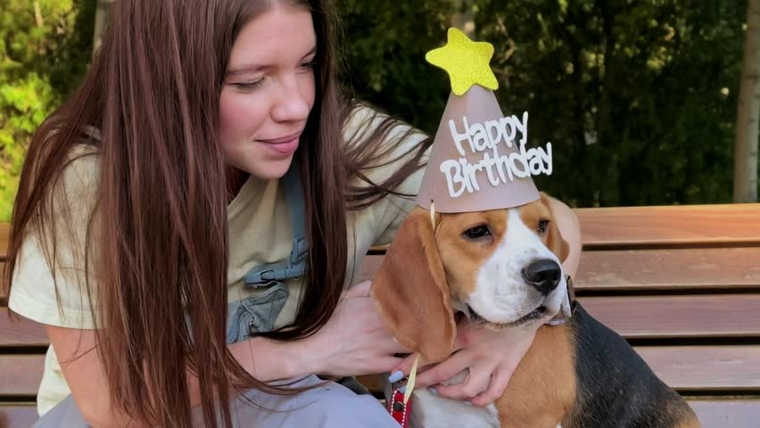 Woman Hugging Beagle Wearing Happy Birthday Hat Outdoors