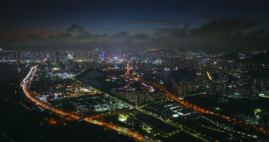 Aerial drone night view of the illuminated city skyline with highway traffic and skyscrapers in Shenzhen, China