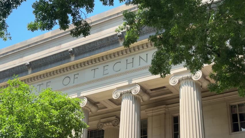 Close-up of the Massachusetts Institute of Technology facade with classical columns and tree branches framing the building.