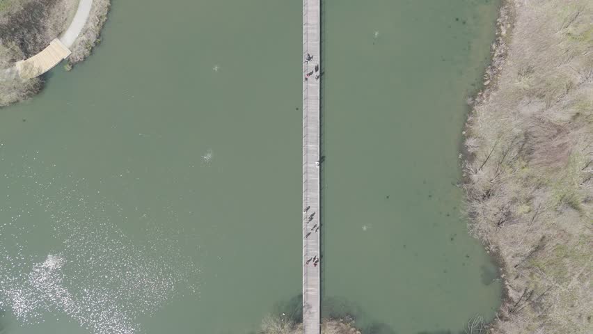 A Drone view of a long bridge crossing water at Beckley Creek Park in Louisville Kentucky in spring
