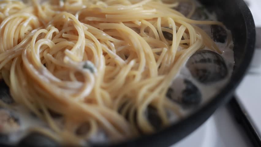A tempting close-up of spaghetti served with fresh seafood and clams. The pasta is perfectly cooked and mixed with delicious shellfish in a savory sauce. Ideal for Italian seafood cuisine and Mediterranean food photography.