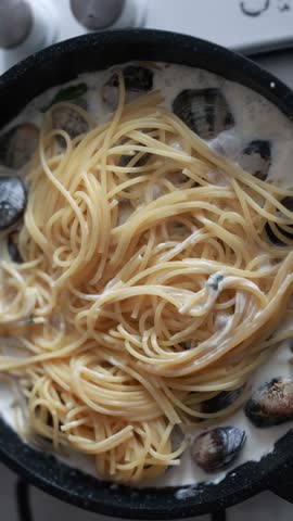 A tempting close-up of spaghetti served with fresh seafood and clams. The pasta is perfectly cooked and mixed with delicious shellfish in a savory sauce. Ideal for Italian seafood cuisine and Mediterranean food photography.