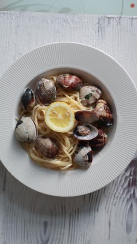 A tempting close-up of spaghetti served with fresh seafood and clams. The pasta is perfectly cooked and mixed with delicious shellfish in a savory sauce. Ideal for Italian seafood cuisine and Mediterranean food photography.