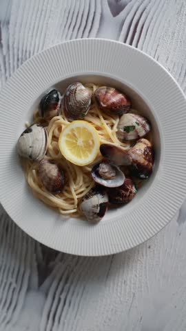 A tempting close-up of spaghetti served with fresh seafood and clams. The pasta is perfectly cooked and mixed with delicious shellfish in a savory sauce. Ideal for Italian seafood cuisine and Mediterranean food photography.