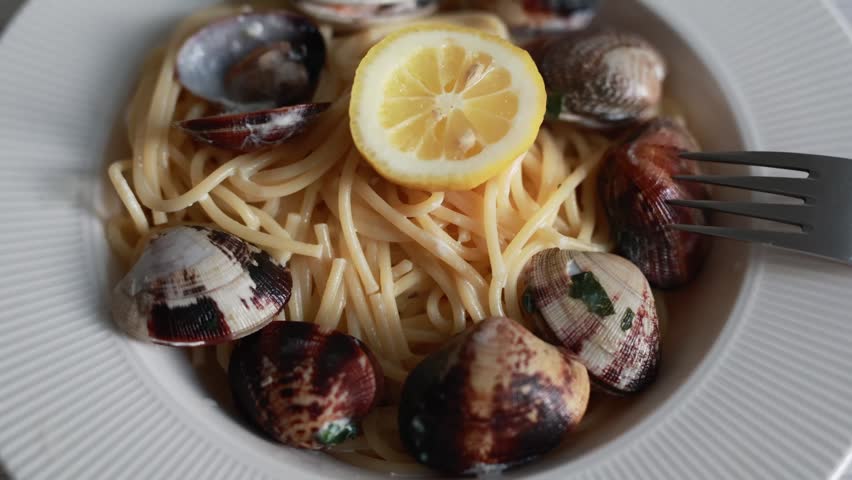 A tempting close-up of spaghetti served with fresh seafood and clams. The pasta is perfectly cooked and mixed with delicious shellfish in a savory sauce. Ideal for Italian seafood cuisine and Mediterranean food photography.