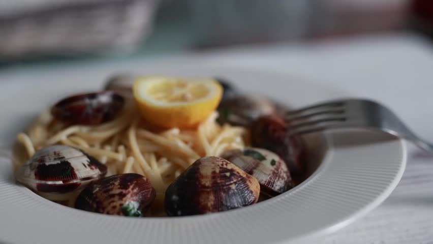 A tempting close-up of spaghetti served with fresh seafood and clams. The pasta is perfectly cooked and mixed with delicious shellfish in a savory sauce. Ideal for Italian seafood cuisine and Mediterranean food photography.