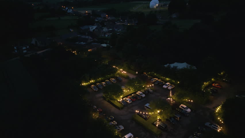 Aerial night scene of parking lot with glowing light lines, parking spaces illuminated.