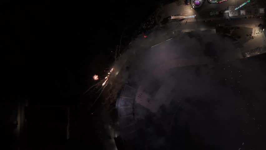 Cinematic aerial drone shot of vibrant fireworks bursting over a professional baseball stadium and city lights, capturing the excitement of a night game celebration.
