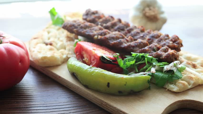 Close-up of traditional Turkish Adana kebab served with grilled vegetables