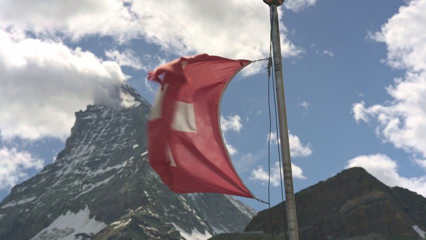 National flag of switzerland waving in the wind with the matterhorn mountain in the swiss alps