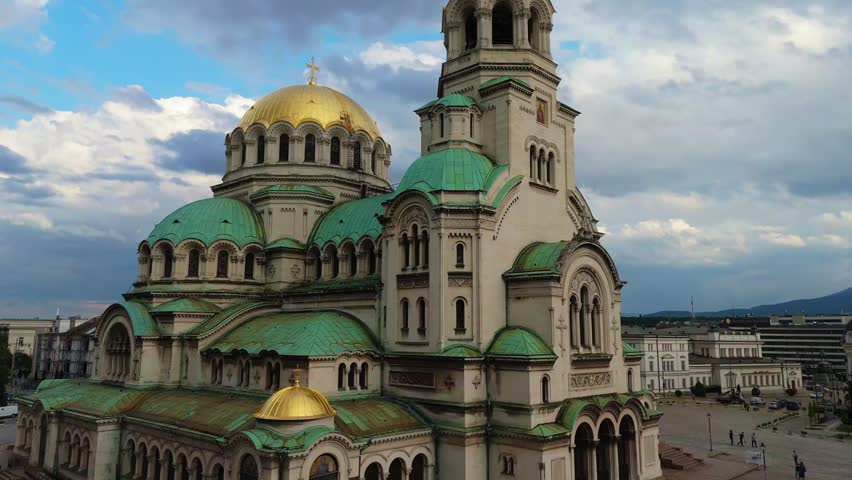 aerial drone flight framing the grand architecture and green copper domes of the Alexander Nevsky Cathedral in Sofia, Bulgaria. Iconic Orthodox Christian monument.
