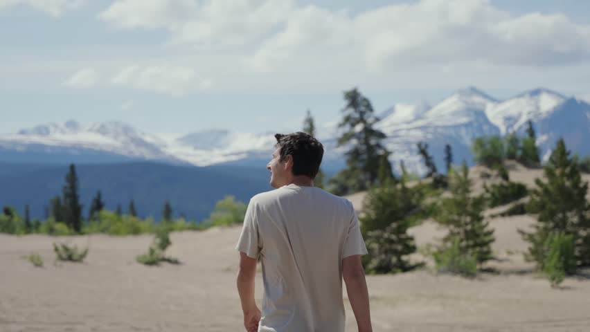 Man walking in Carcross desert looking at snow capped mountains in Yukon, Canada