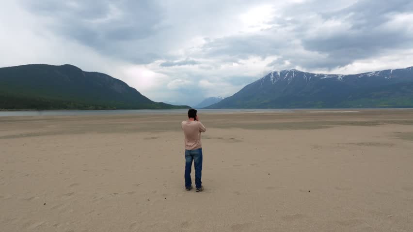 Man photographing beach at Carcross in Yukon, Canada