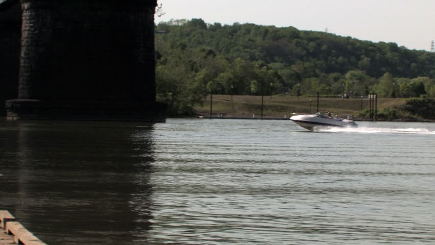 A speedboat zips under a railroad bridge on the Ohio River.