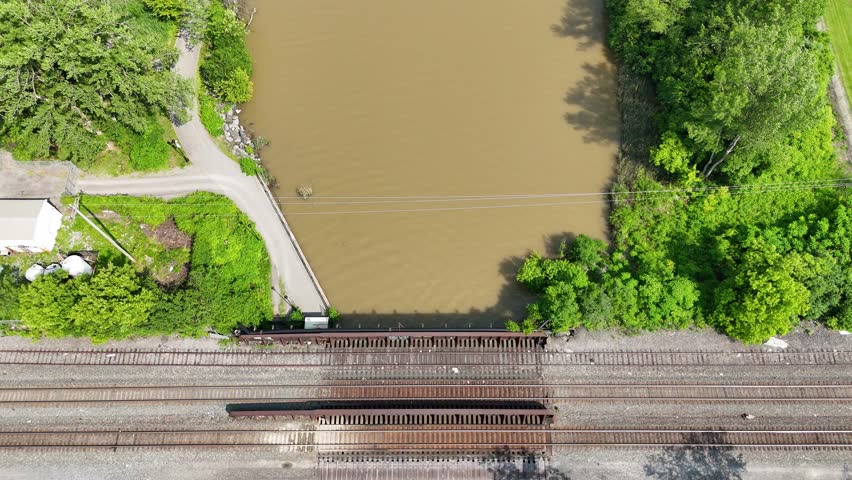 Railroad tracks that cross over a river that leads into the city skyline.