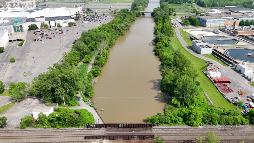 Railroad tracks that cross over a river that leads into the city skyline.