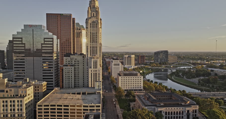 Columbus Ohio Aerial v65 low flyover Front St, capturing riverfront downtown cityscape and East Bank Park along Scioto river at sunset golden hour - Shot with 8k camera