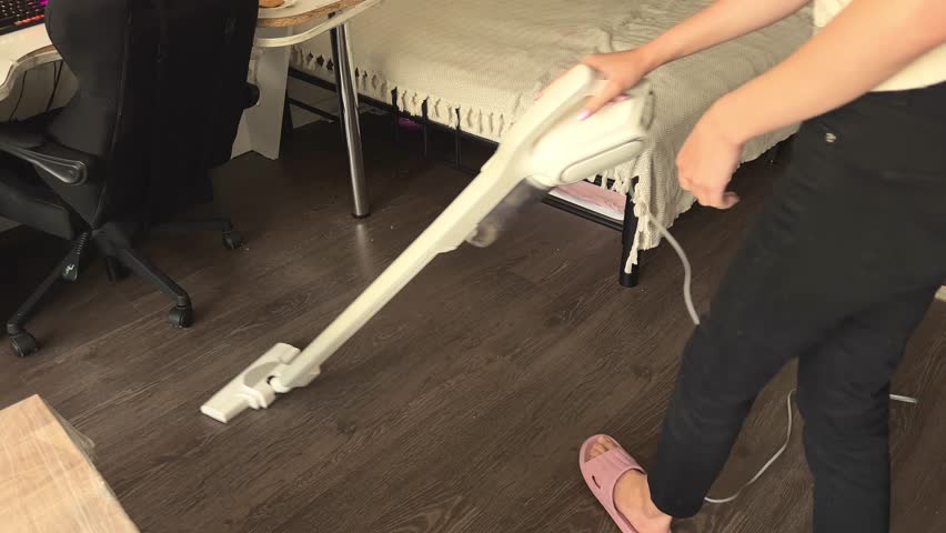 Woman cleaning house floor with a modern cordless vacuum cleaner
