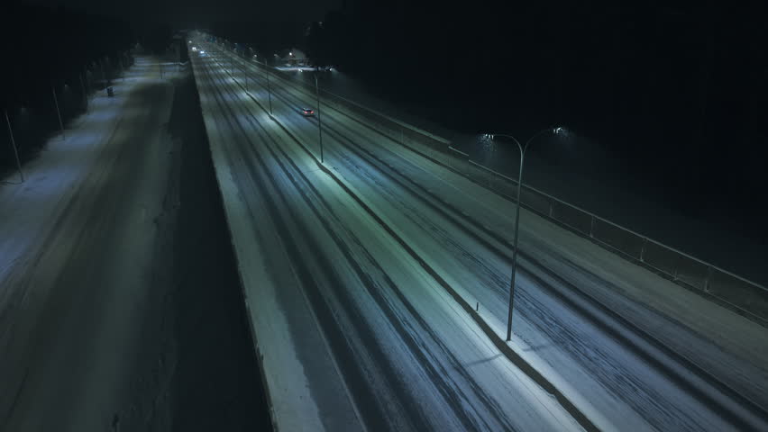 Car lights streak across quiet highway, Moonlit highway with moving lights and reflective surface shine