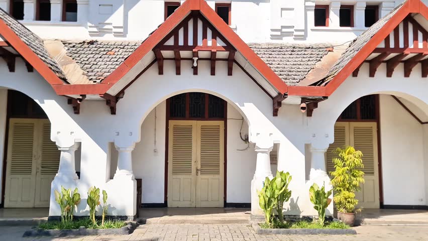 Madiun, 8 July, 2026: Historic Dutch colonial architecture building in Indonesia with sturdy white facade, red tile roof, and classic arched louvered doors, built in 1912.