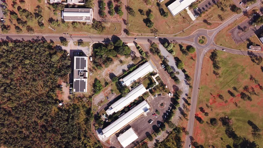 Direct overhead drone shot capturing the unique radial and circular architecture of buildings at the University of Brasília (UnB) campus among trees