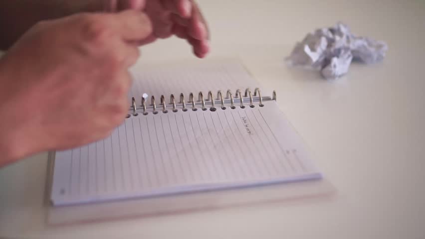Hand writing text in spiral notepad on white table an then make mistake. Close-up shot, business and work concept, office productivity and note-taking.