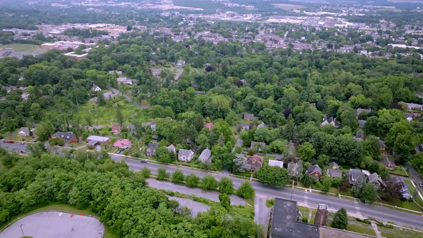 Smooth aerial view moving over a tree-filled residential neighborhood with homes, streets and urban development in Harrisburg, Pennsylvania with drone video moving in.
