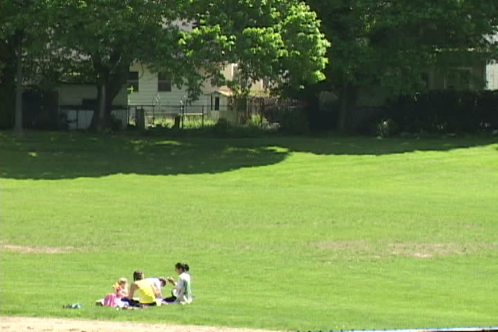 Two friends enjoy beautiful day in the park with their children.
