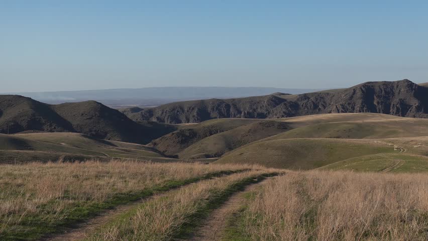Mountain landscape, path going down, early spring, fresh green grass growing over old dry grass