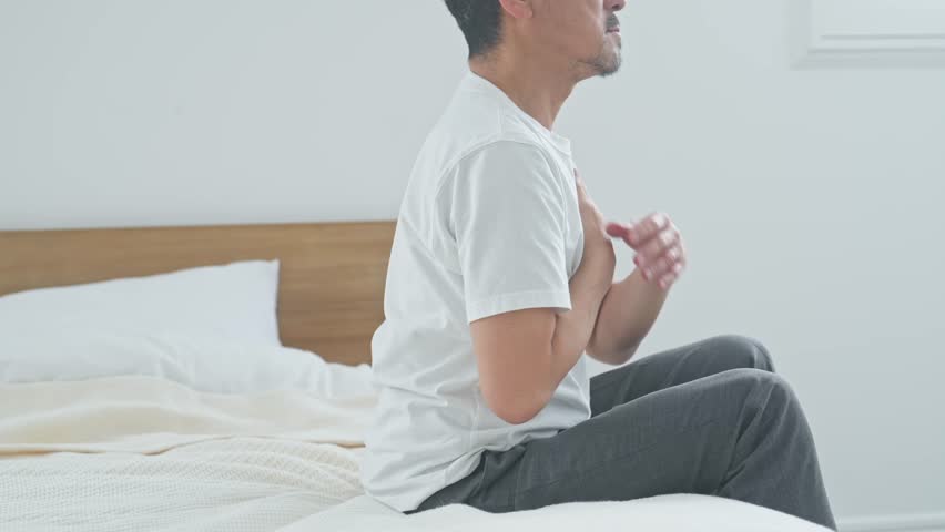 Senior man suffering from stiff shoulders. Fatigue, tiredness, bed, middle-aged, stress, aging, "frozen shoulder" (shoulder pain associated with aging).