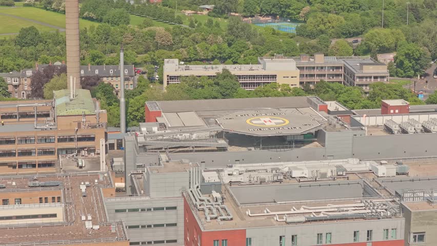 Royal Victoria Infirmary rooftop helipad dominates the hospital campus in Newcastle upon Tyne, Tyne and Wear, England, beside emergency medical facilities and Leazes Park, slow drone lateral slide.