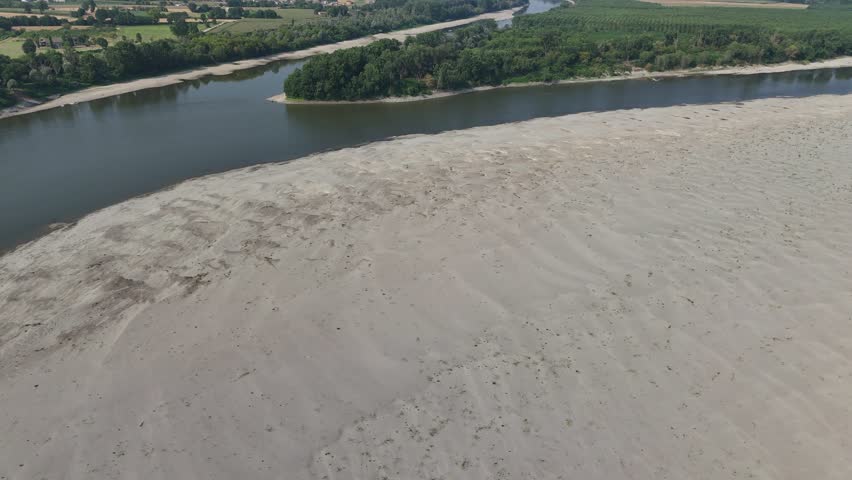 Po River showing severe drought conditions, wide dry riverbed with stranded boats along the banks, a result of climate change and extreme heatwave in Italy