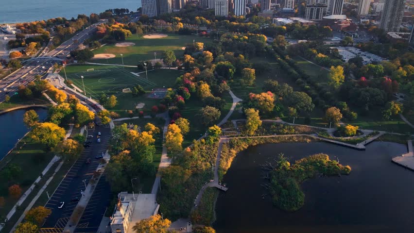 An aerial view of Chicago skyline stretching toward Lake Michigan, with urban sprawl framed by green parklands and shimmering waters