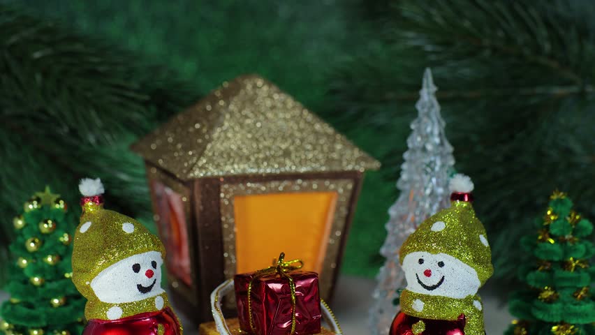 Two snowmen with a gift on a sled and letters against the background of a Christmas lantern and fir trees