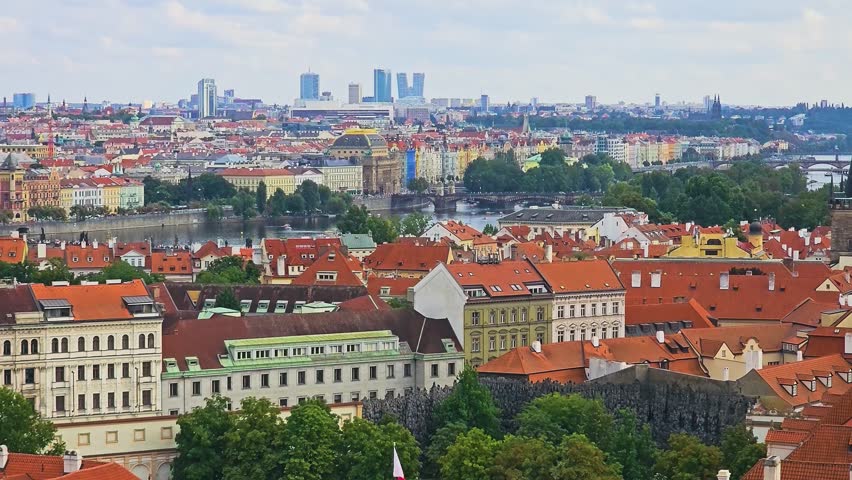 Telephoto view of Prague, Czech Republic, showing Charles Bridge, Vltava River, red rooftops, green copper domes, Old Town towers, Zizkov TV Tower, and historic city landmarks.