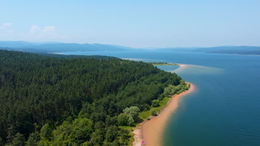 Shiroka polyana reservoir scenic drone panoramic view green pine forest shoreline clear blue water hills background summer sunny day travel destination concept Bulgaria.