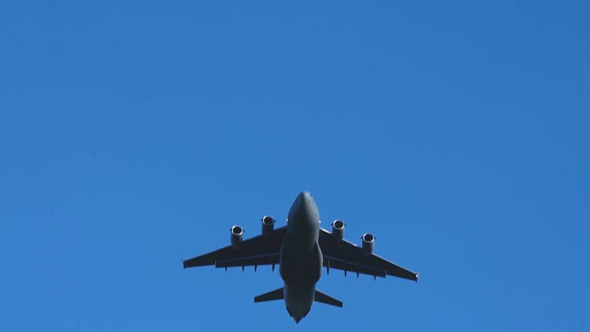 Military Cargo Aircraft Conducting Precision Paratrooper Airdrop During Airborne Training Mission Beneath Clear Blue Sky.
