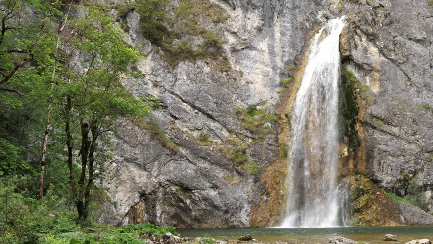 Powerful waterfall, cascade falling down a rocky cliff in the forest