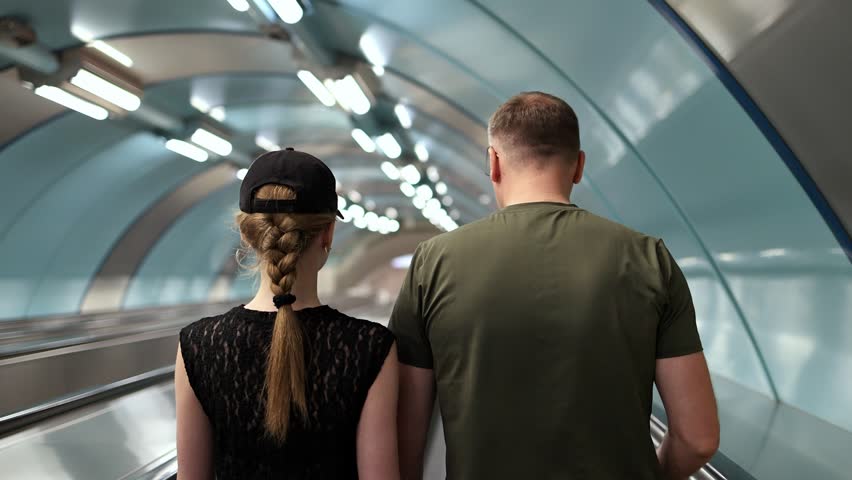 People walking into the subway, slow motion, view from behind.