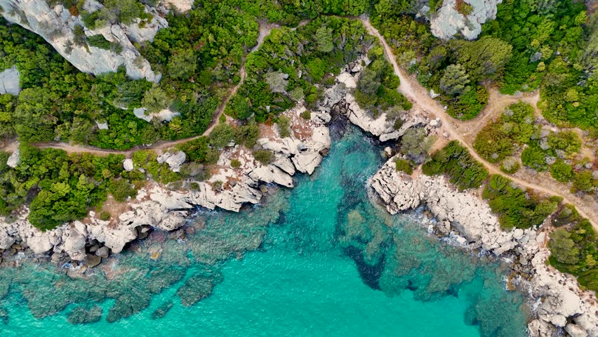 Aerial View of Turquoise Sea and Rocky Coastline, Lush Green Vegetation, Clear Water with Coral Reef and Small Waves. Holiday in Sardinia.